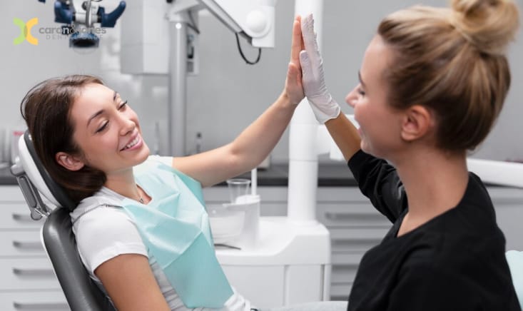 Cheerful dental patient giving a high-five to her dentist after a successful appointment
