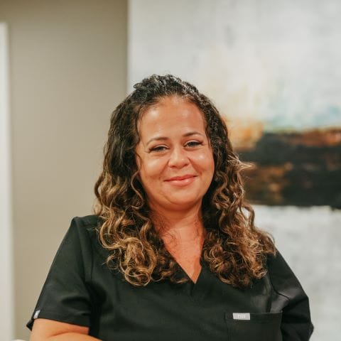 Headshot of Brooke Radtke, Hygiene Assistant with curly hair and a welcoming smile poses in a modern dental office