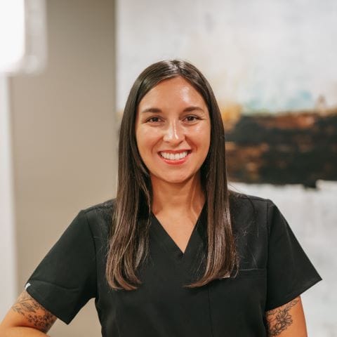 Headshot of Kristy Anderson, Dental Assistant with straight dark hair poses confidently in a modern dental office