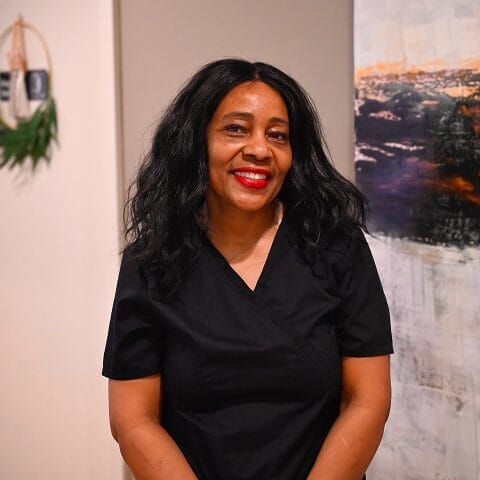 Headshot of Nancy, Dental Assistant in black scrubs smiles confidently in a modern dental office