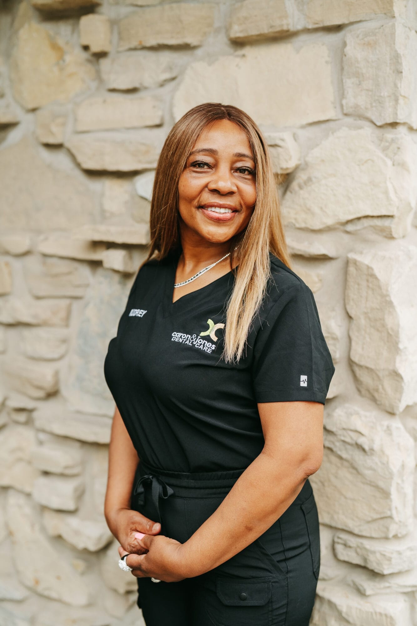 Headshot of Nancy, Dental Assistant in black scrubs smiles confidently in a modern dental office