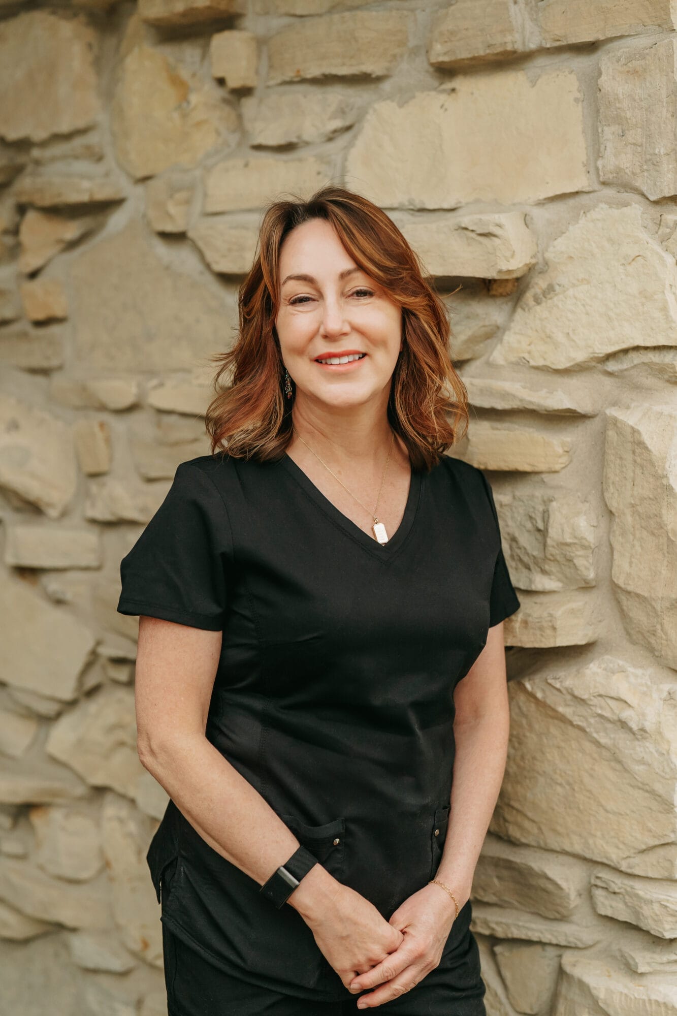 Headshot of Dr. Kathryn Jones, D.D.S. in black scrubs smiles confidently while standing in a brightly lit dental office hallway