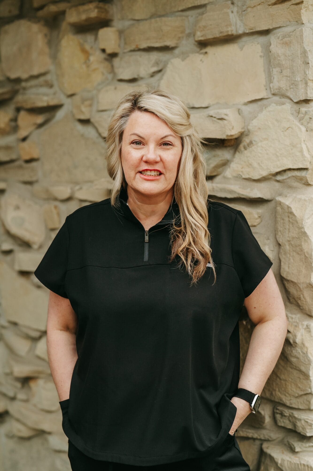 Headshot of Heather Kirby, Practice in black scrubs sits at the reception area, ready to greet patients with a welcoming smile Administrator 