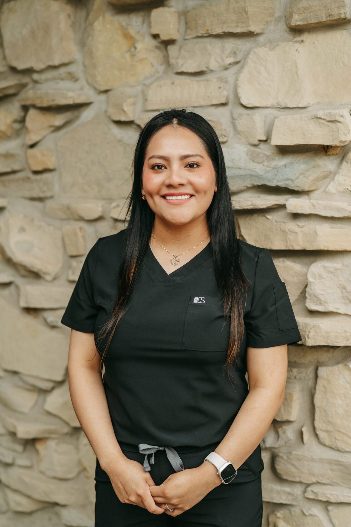 Headshot of Nancy, Dental Assistant in black scrubs smiles confidently in a modern dental office